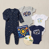 A baby gift set featuring four infant clothing pieces and two books on a light beige textured background: a navy footed sleeper with space motifs, a light gray bodysuit with a galaxy print, a white bodysuit with a cute Earth graphic and 'Hello World!' text, and a navy bodysuit with a space-themed graphic. A book titled '8 Little Planets' by Chris Facio and a round wooden name plaque are also included.