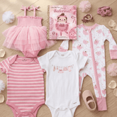 Collection of baby clothing and accessories on a wooden surface, including pink romper, striped onesie, and ballet-themed items.