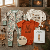 Baby clothing and accessories on a wooden surface with a fireplace in the background