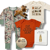 Collection of baby clothing and toys including a onesie, romper, and stuffed animal on a white background.
