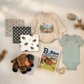 Baby clothing and toys with a nature-themed design on a light background