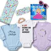 Collection of baby items including onesies, a book, and sunglasses on a white background