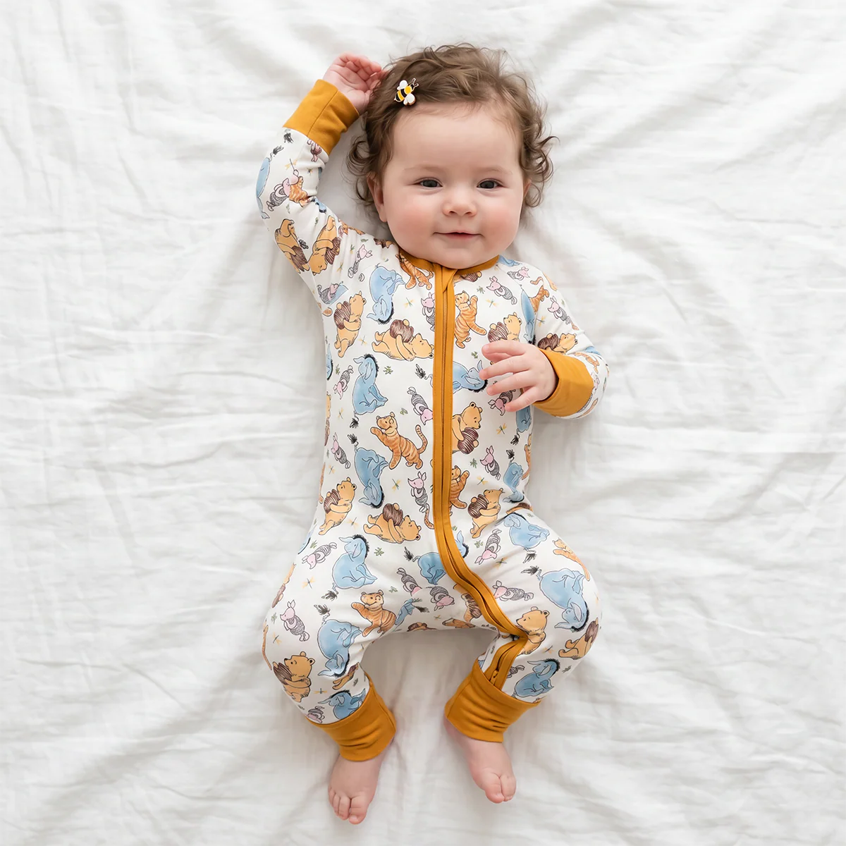 Baby wearing a patterned onesie lying on a white blanket