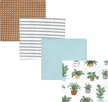 Four fabric or paper swatches arranged overlapping on a white background: a tan square with white polka dots, a white square with black dash marks, a light blue square, and a white square with a green potted plant pattern.