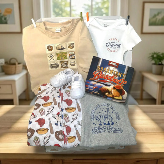 Collection of baseball-themed clothing and a book on a wooden surface.