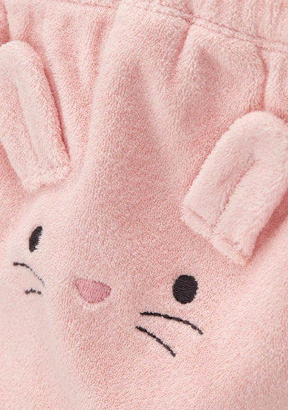 Close-up of a soft pink plush fabric with embroidered bunny face details, including black embroidered eyes and whiskers and a small pink nose.