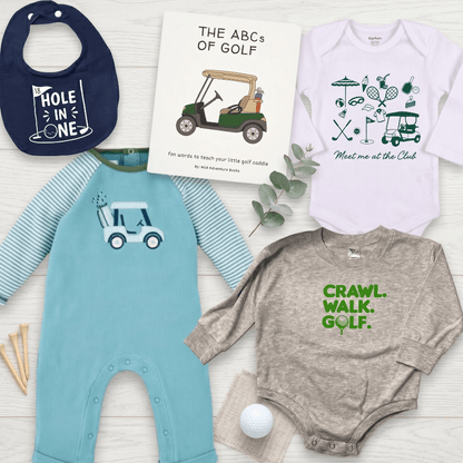 Collection of children's clothing and a book with golf-themed designs on a light wooden surface.