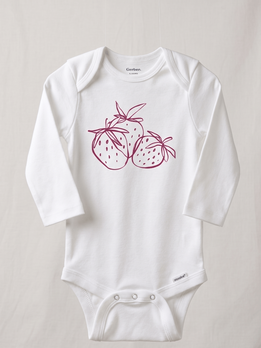 White baby onesie with pink strawberry design on a light gray background