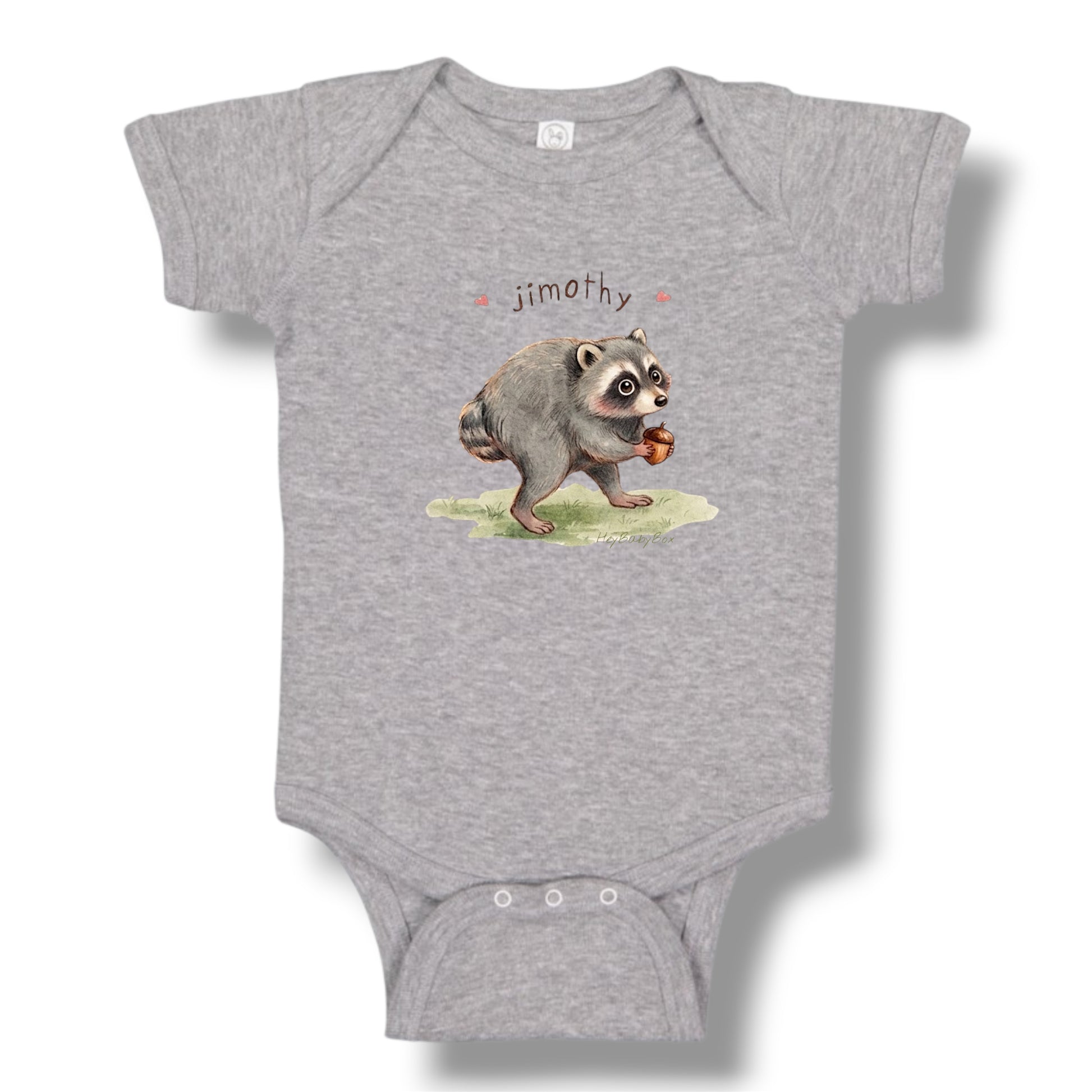 A heather gray short-sleeve baby bodysuit featuring a watercolor-style illustration of a raccoon holding an acorn with the name 'jimath' printed above it, shown on a white background with a soft drop shadow.