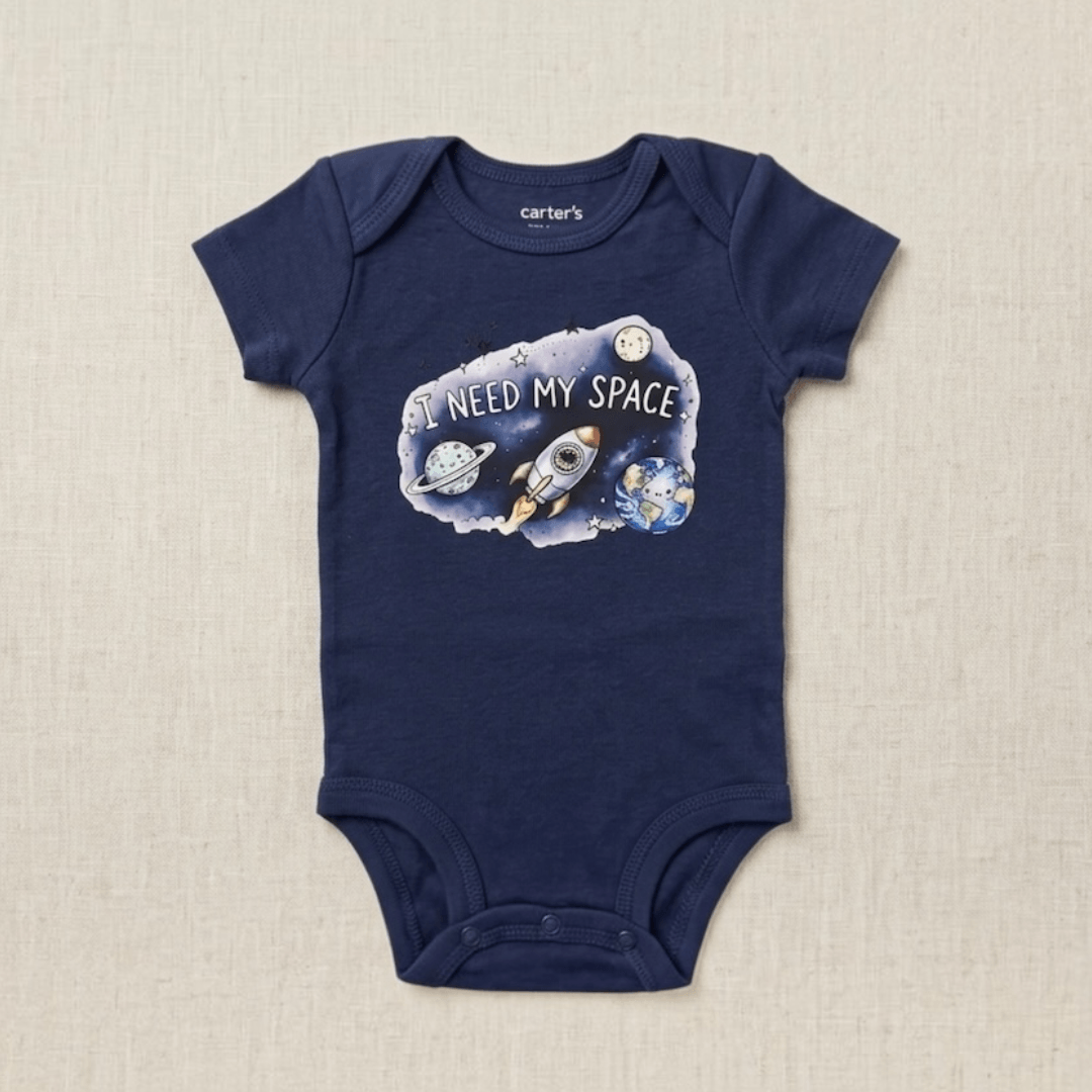 A navy blue short-sleeve baby bodysuit by Carter's, featuring a graphic print of a rocket ship, planets, and the text 'I NEED MY SPACE' on a textured beige background.