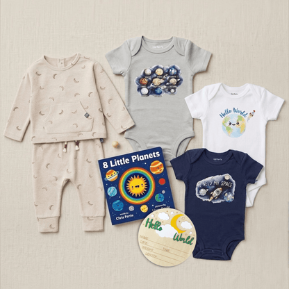 A baby clothing set arranged on a light beige fabric background, including a cream long-sleeve top and matching pants with small celestial prints, a light gray short-sleeve bodysuit with a colorful planets graphic, a white bodysuit with a blue Hello World graphic, a navy bodysuit with a space-themed graphic, a children's book titled 8 Little Planets, and a round wooden name plaque.