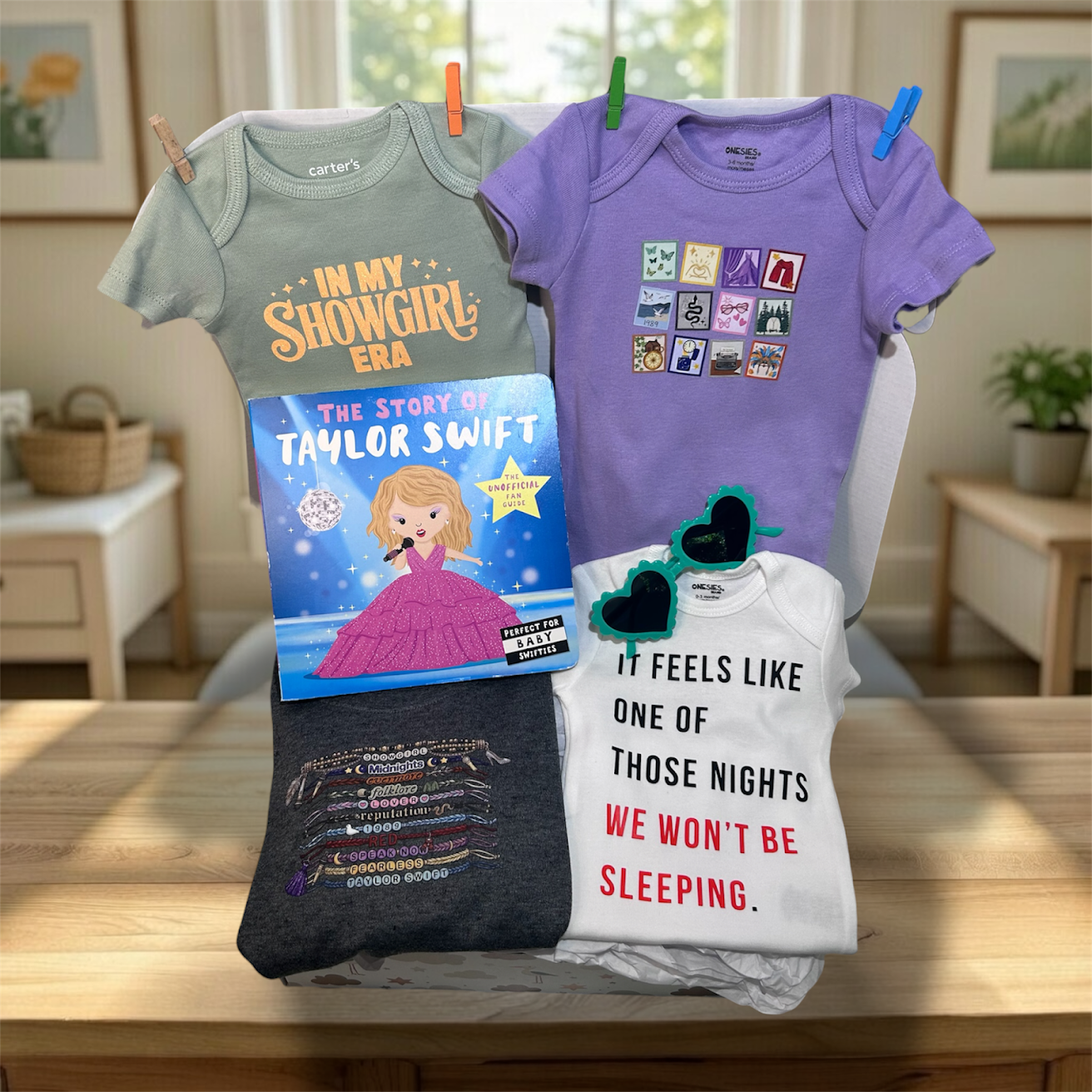 Collection of baby clothes and a book on a table with a home setting in the background