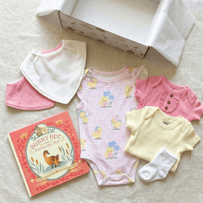 Baby clothing and book set on a neutral background