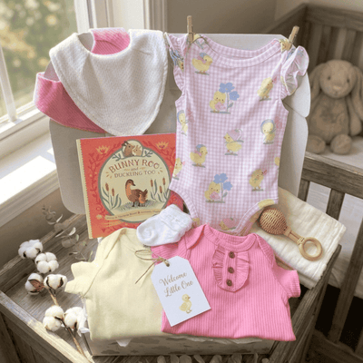 Baby clothing and items on a changing table with a book and teddy bear in the background.