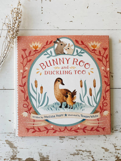 Children's book titled 'Bunny Roo and Duckling Too' on a wooden surface.