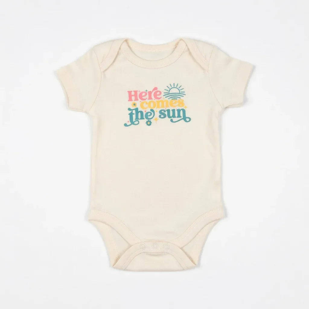 Beige baby onesie with 'Here comes the sun' text on a white background