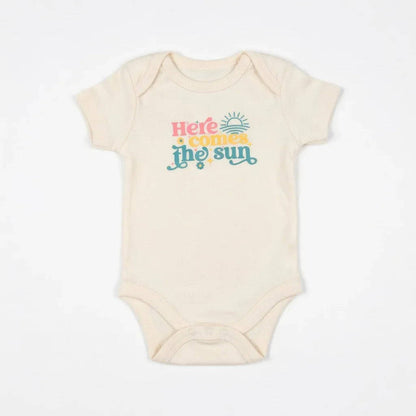 Beige baby onesie with 'Here comes the sun' text on a white background