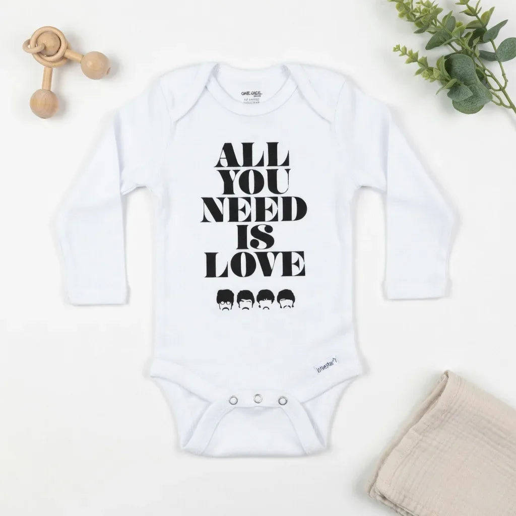White baby onesie with 'All You Need Is Love' text on a white background