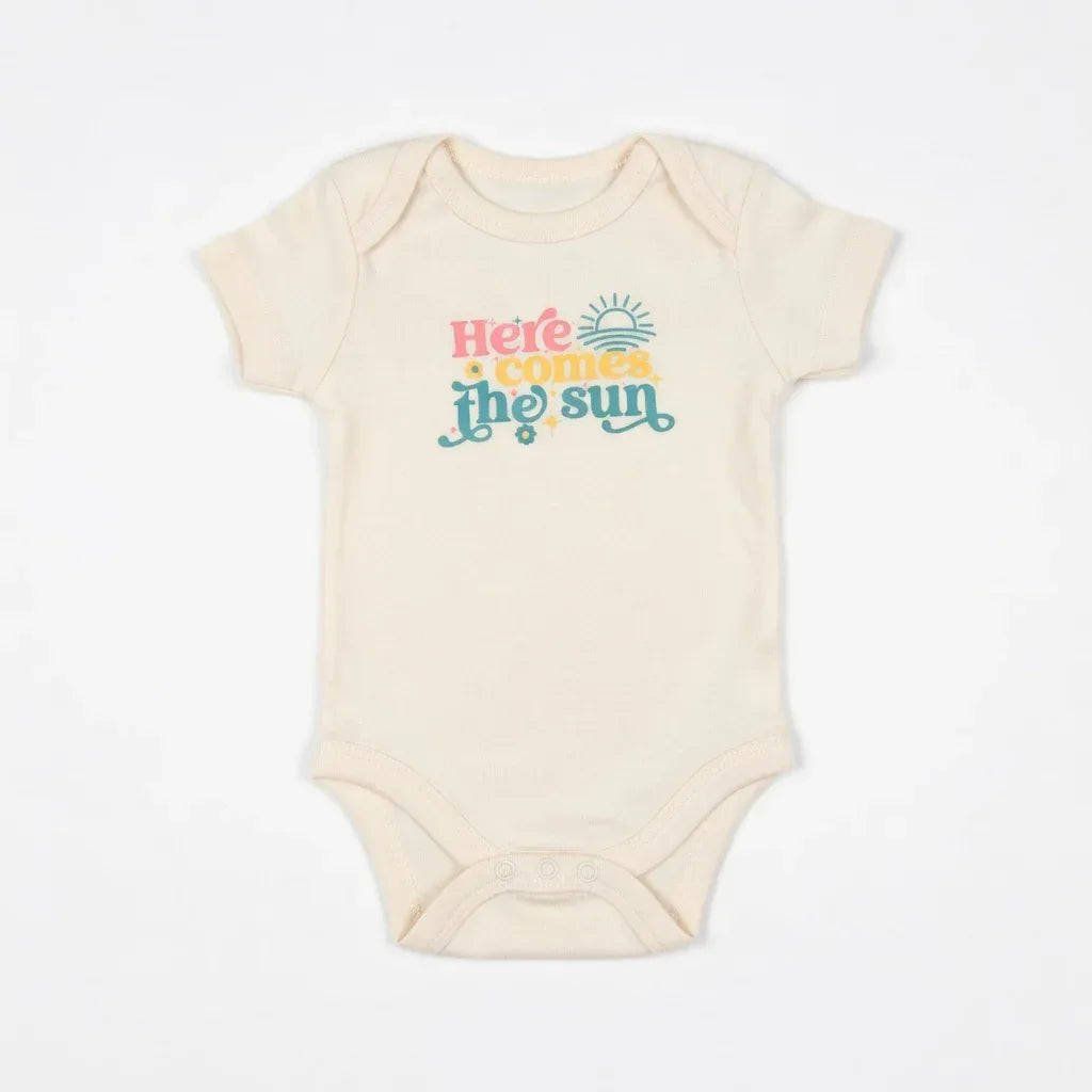 Beige baby onesie with 'Here comes the sun' text on a white background