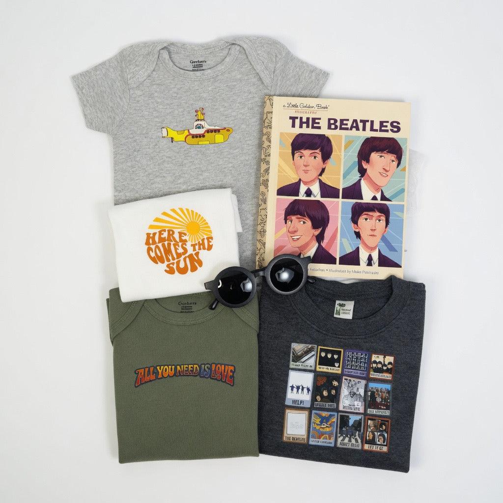 Collection of Beatles-themed merchandise including t-shirts and a book on a white background