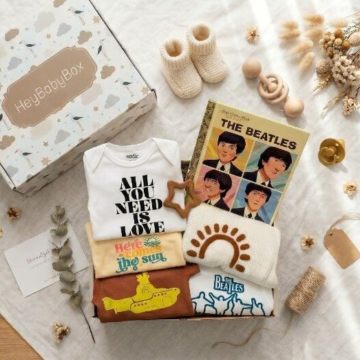 Baby-themed gift set with 'Hey Baby Box' on a light surface, featuring baby clothes and books.