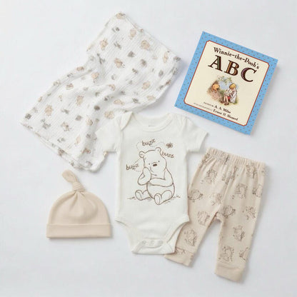 Baby clothing set with onesie, pants, hat, and book on a light background