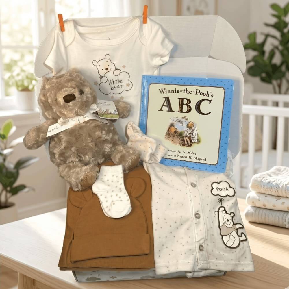 Baby gift set with teddy bear, clothes, and book on a table.