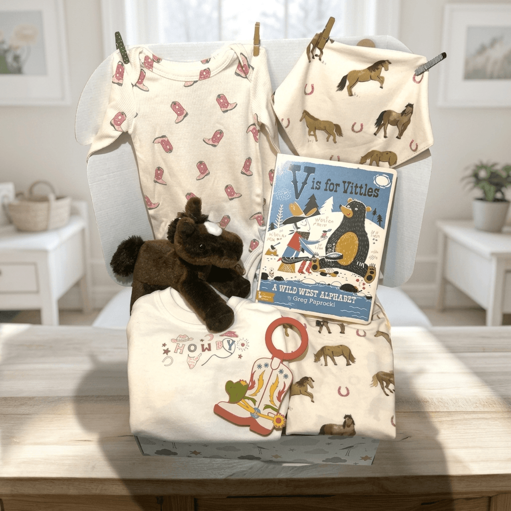 Baby items including a onesie, blanket, plush toy, and book on a table in a bright room.