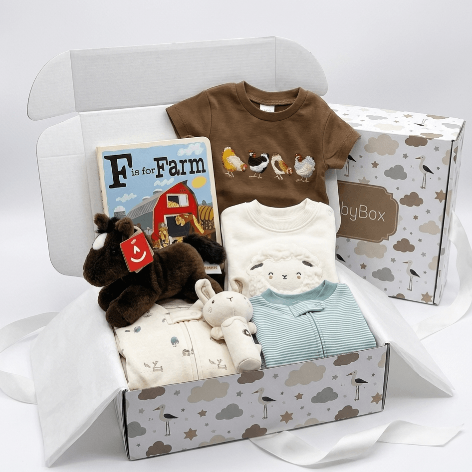 A baby gift box set from byBox featuring a brown short-sleeve t-shirt with a chicken graphic, a cream zippered romper, a light blue long-sleeve top, a plush toy, and a 'Facts for Farm' book, all arranged inside an open patterned box with a branded box behind it.