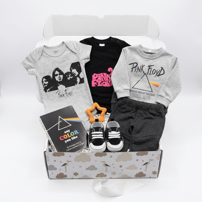 A curated gift box set for kids featuring a gray band t-shirt, a black Pink Floyd t-shirt, a gray sweatshirt with a Pink Floyd prism graphic, black shorts, black and white sneakers, a book, and a star-shaped rattle inside a cloud-patterned box.