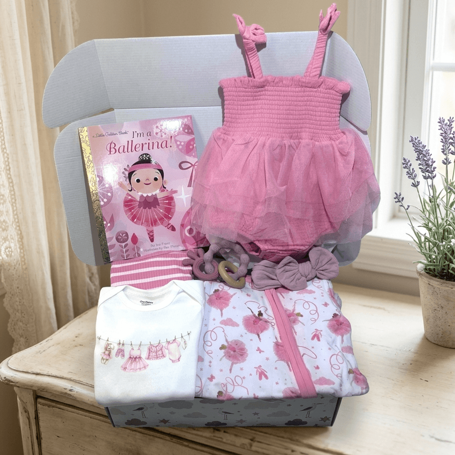 Pink baby outfit with matching blanket and book on a wooden surface.