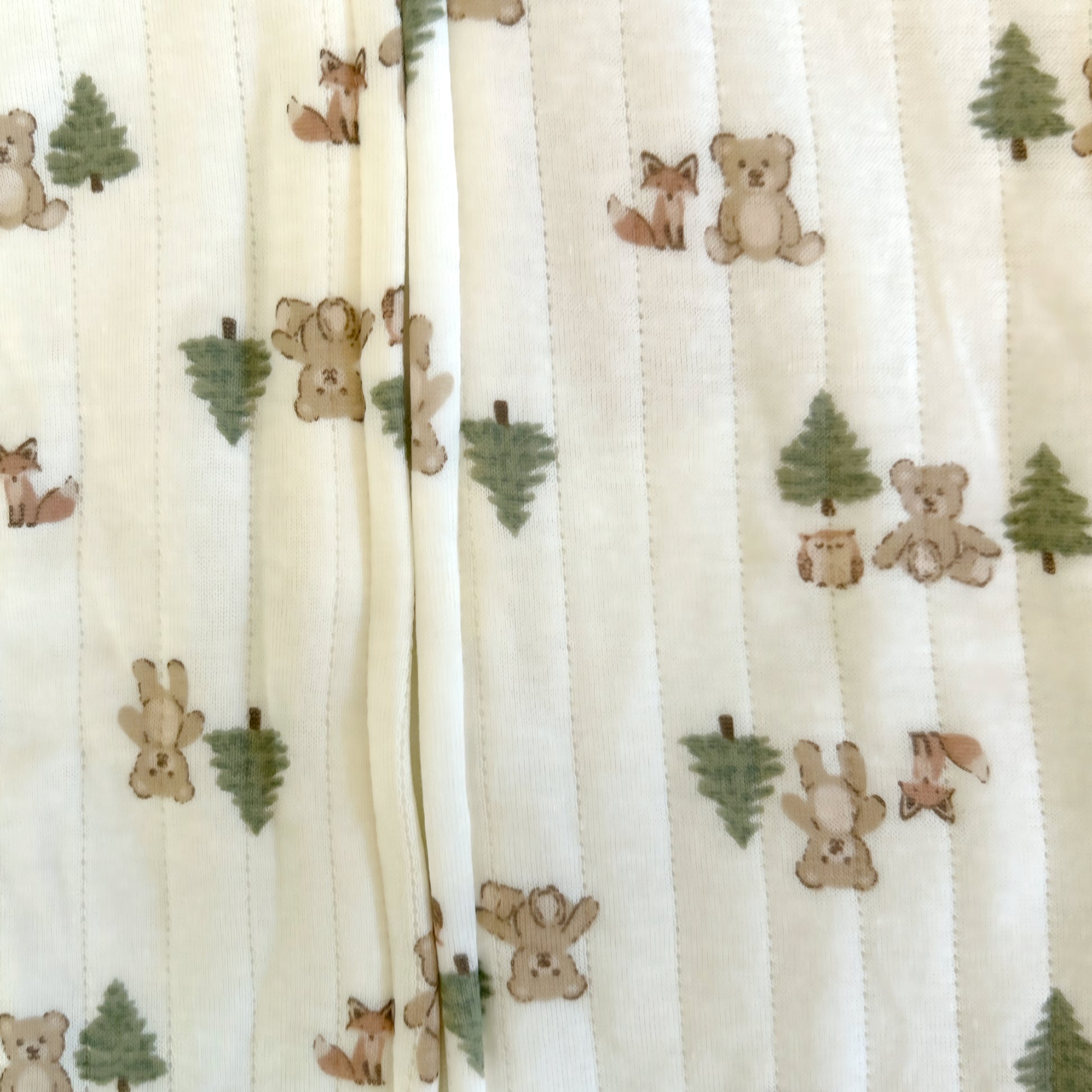 Fabric with teddy bear, fox, and tree pattern on a white background