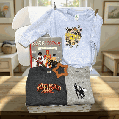 Three t-shirts with 'Fleetwood Mac' design on a table in a room.