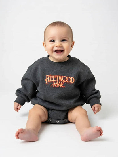 Baby wearing a dark gray sweatshirt with 'Fleetwood Mac' printed in orange on a white background