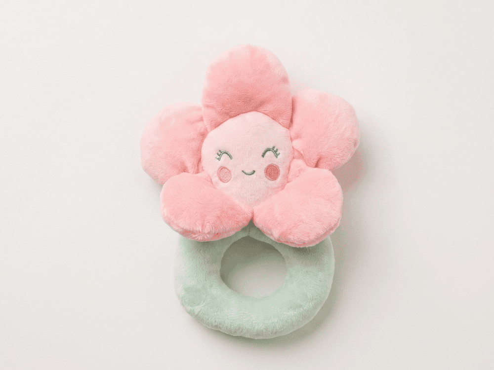 Pink flower-shaped plush toy with a face on a white background