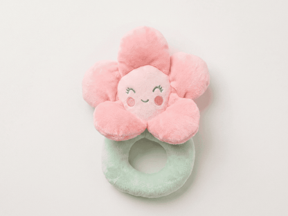 Pink flower-shaped plush toy with a face on a white background