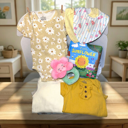 Baby clothing and toys on a table with a book titled 'Little Sunflower'.