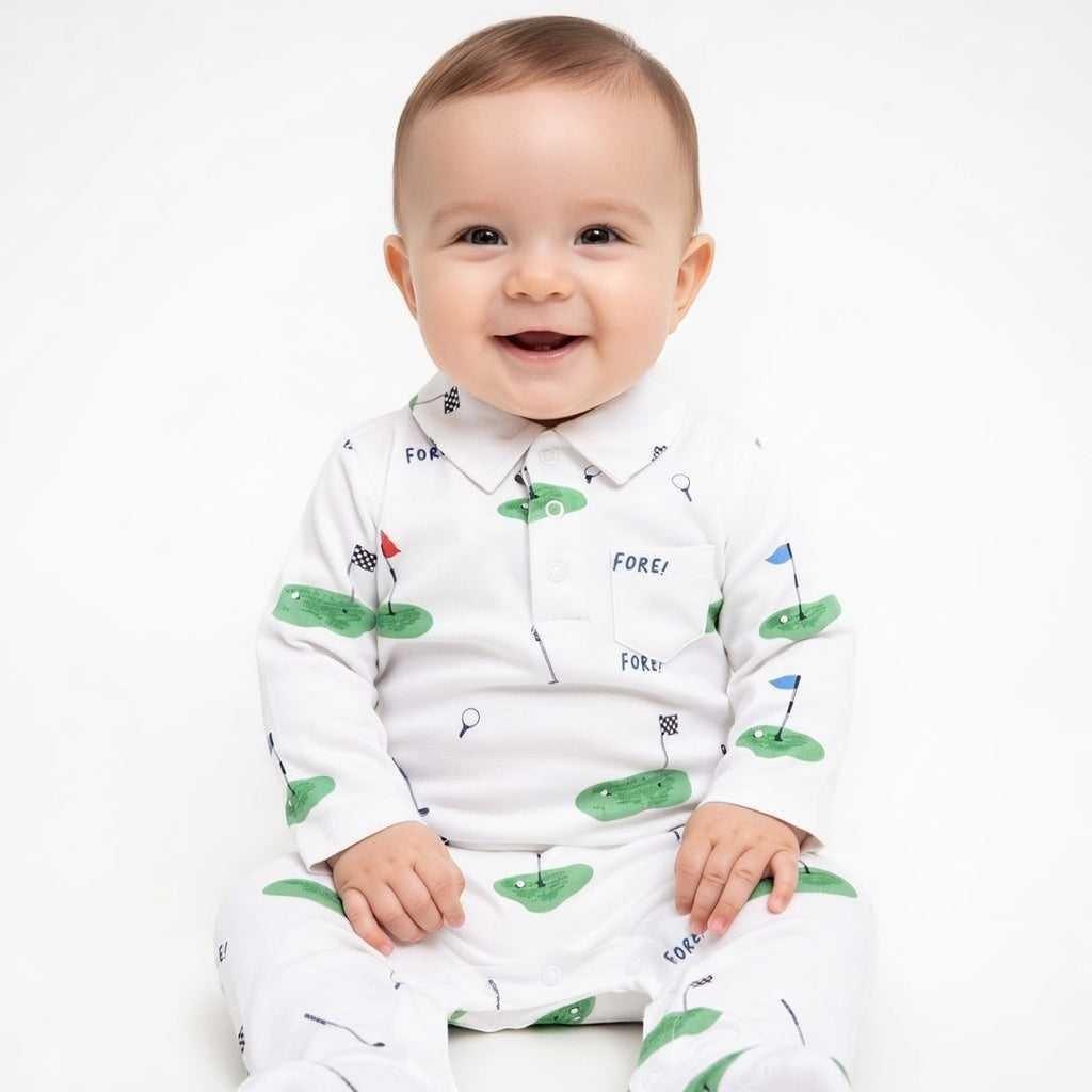 Baby wearing a white long-sleeved romper with a golf course print, featuring green fairways, flags, and "FORE!" text. Hey Baby Box.