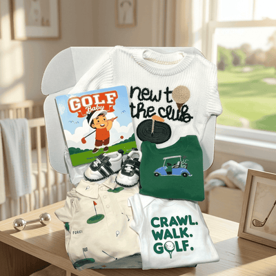 Collection of baby clothing and accessories with golf-themed designs on a table in a room with a window view.