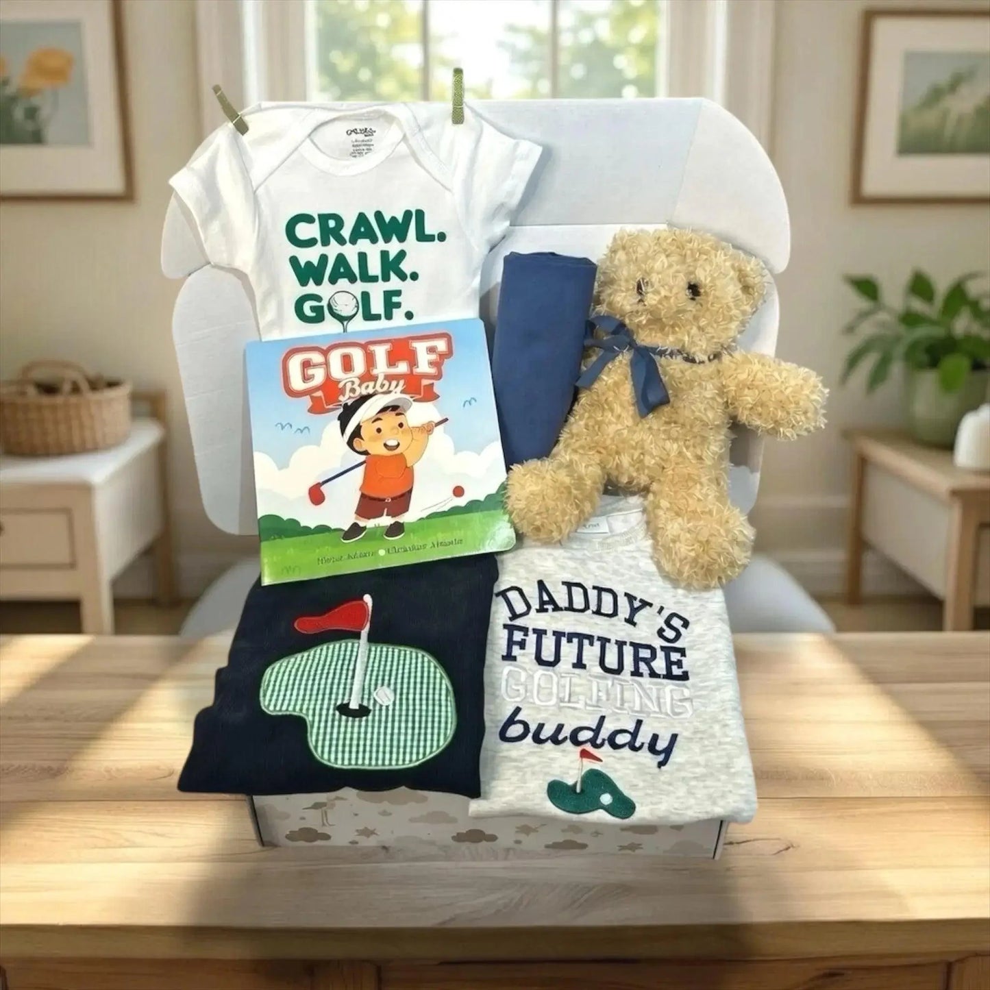 Baby gift set with t-shirt, onesie, book, and teddy bear on a chair.