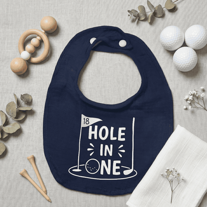 Navy blue bib with '18 Hole in One' print on a neutral background with golf-themed items.