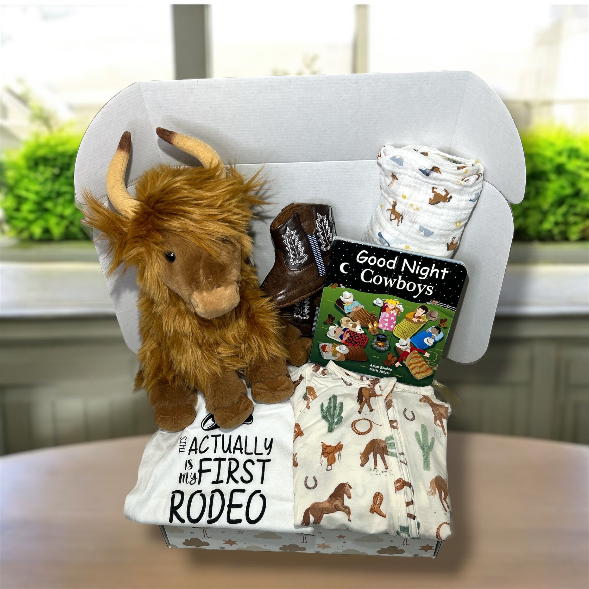 Baby gift set with plush cow, boot, and blankets on a chair