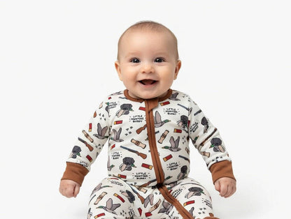 Baby wearing a hunting patterned onesie with brown accents on a white background