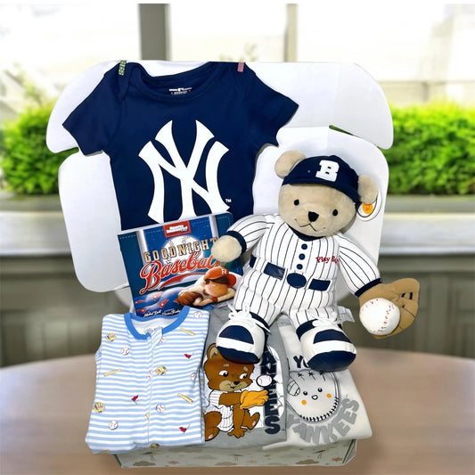 Baby gift set with Yankees-themed items including a onesie, teddy bear, and bib on a white stand.