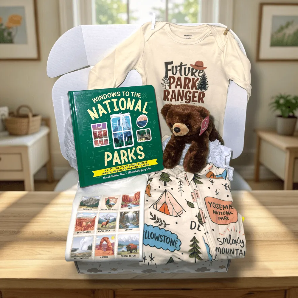 Baby gift set with t-shirt, book, blanket, and teddy bear on a chair.