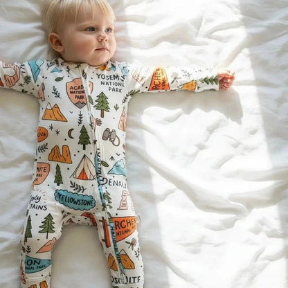 Child wearing a onesie with national park designs on a white blanket