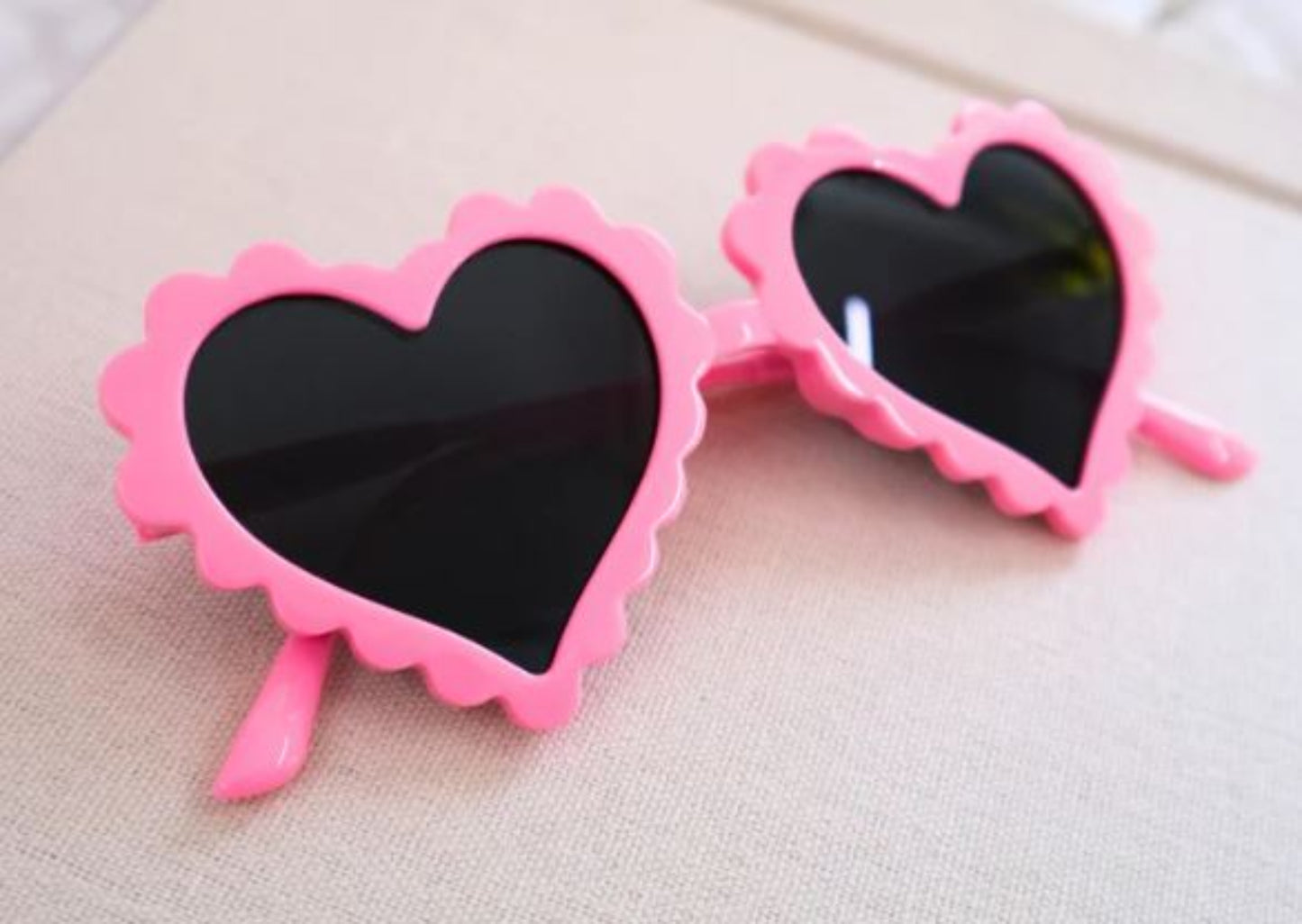 Heart-shaped sunglasses with pink frames on a light background