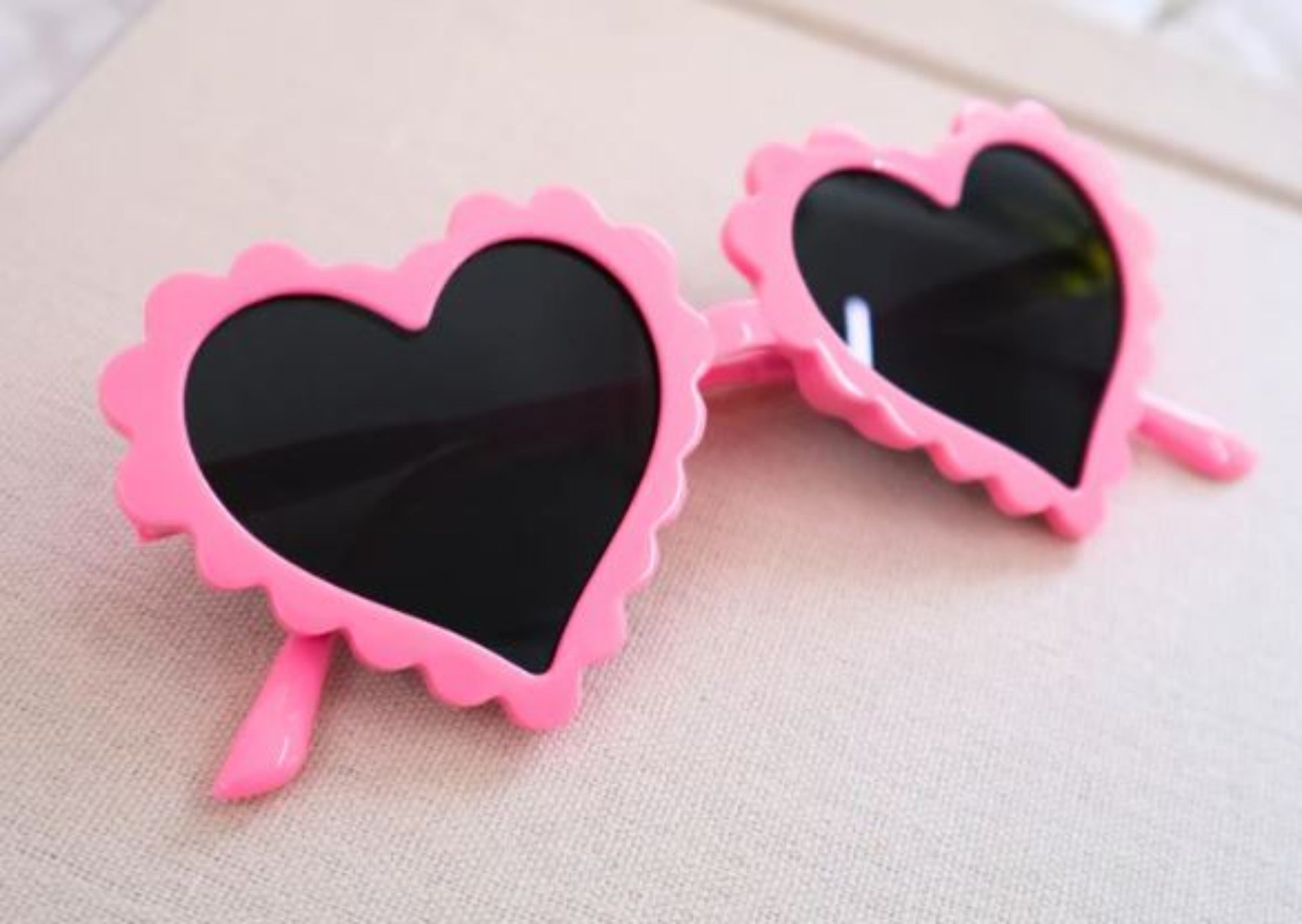 Heart-shaped sunglasses with pink frames on a light background