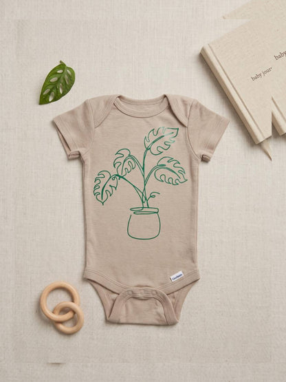 Beige baby onesie with green plant design on a beige background