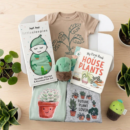 Baby gift set with t-shirt, swaddle blanket, and books on a wooden surface with plants.
